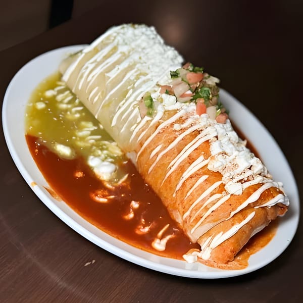 A large Chilaquiles Modern Kitchen burrito, half covered in green sauce and half in red sauce.